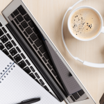 Herramientas del trabajo remoto: Laptop, café, lápiz, audífonos y papel.